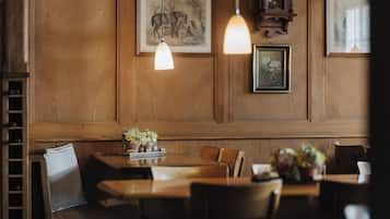 Una habitación con paneles de madera, una mesa de comedor, sillas y lámparas colgantes.
