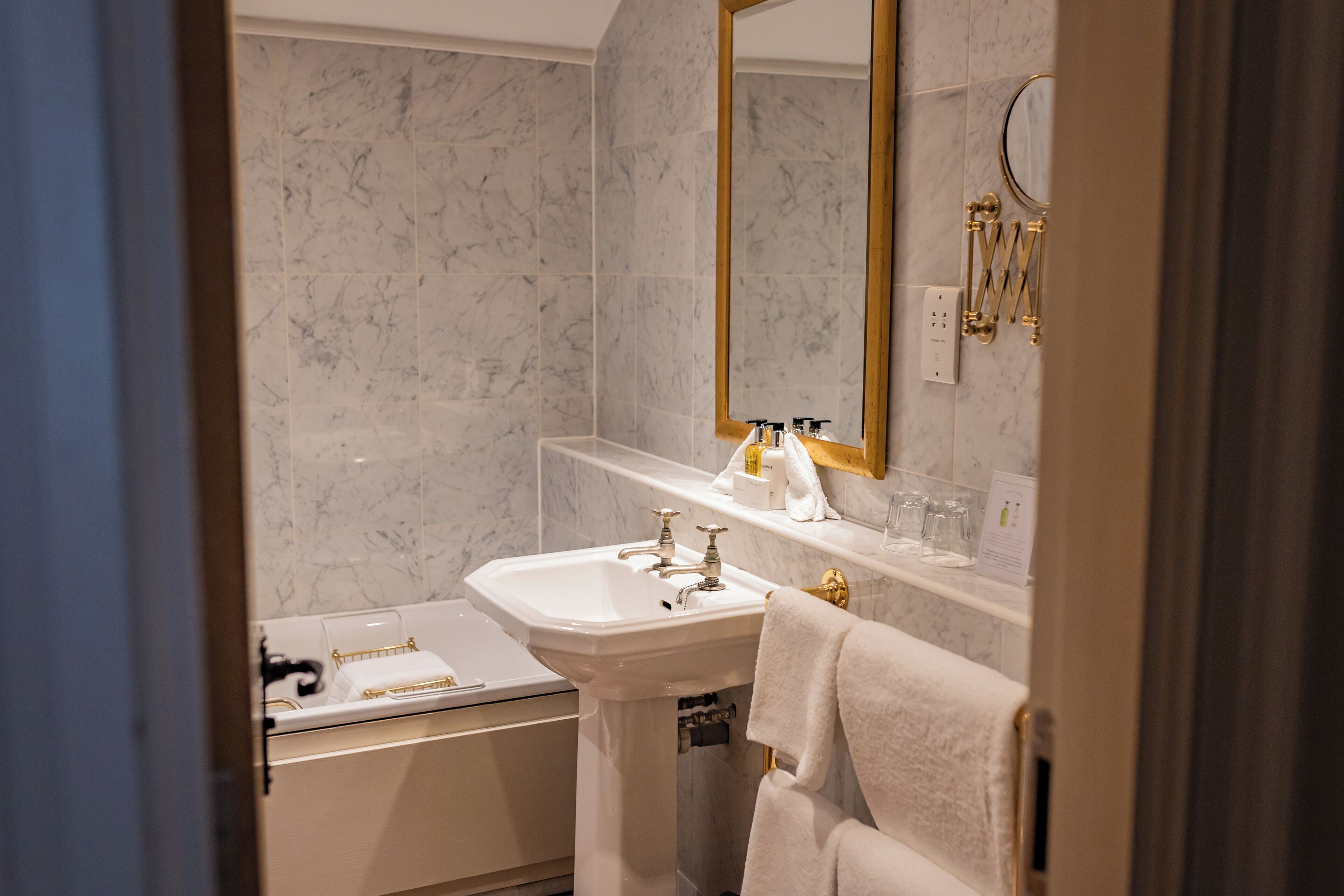 Une salle de bain avec un lavabo blanc, une baignoire et un grand miroir.