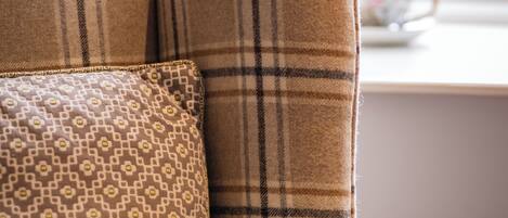 A sofa with a plaid pattern and a patterned pillow.