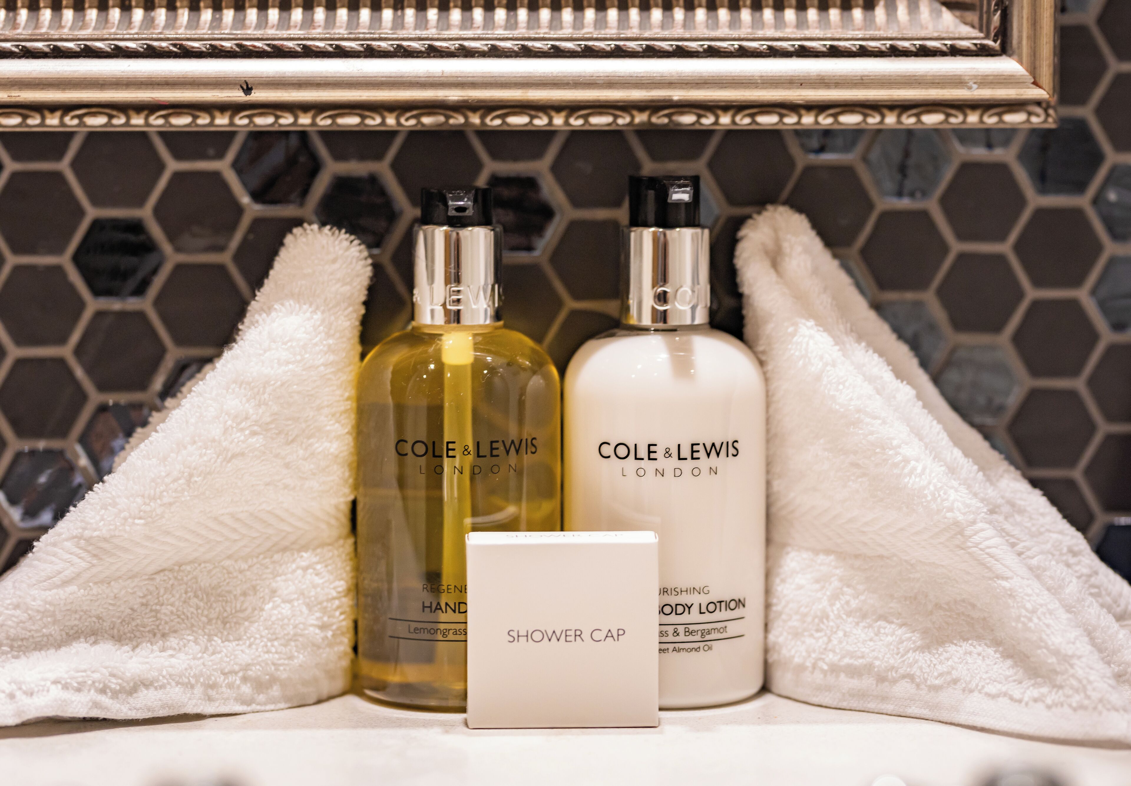 Une salle de bain avec un miroir, deux flacons de lotion et un bonnet de douche.