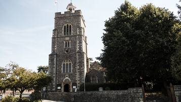 A historic stone church with a tall bell tower, a clock, and a flag on top.