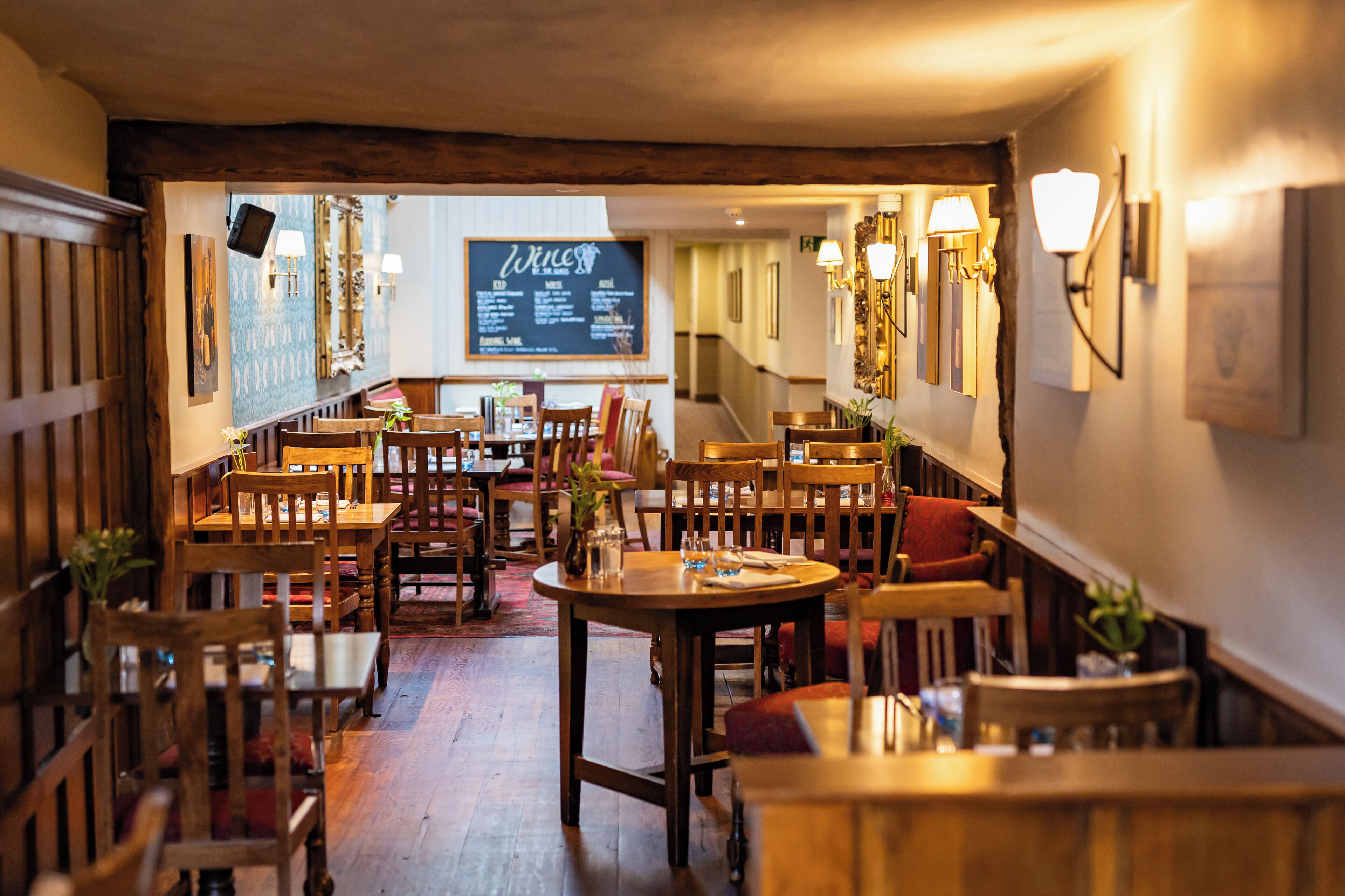 Un restaurante acogedor con muebles de madera y una pizarra con el menú.