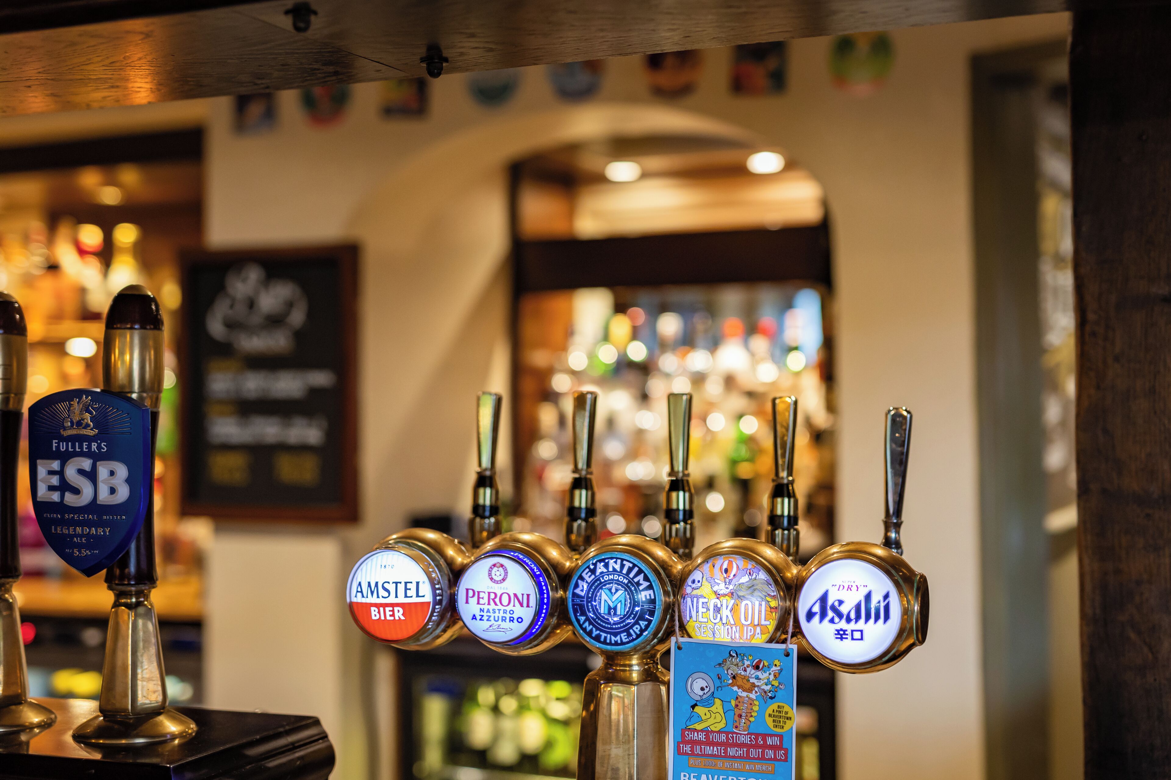 A bar with multiple beer taps, including brands like Fuller's ESB and Asahi.