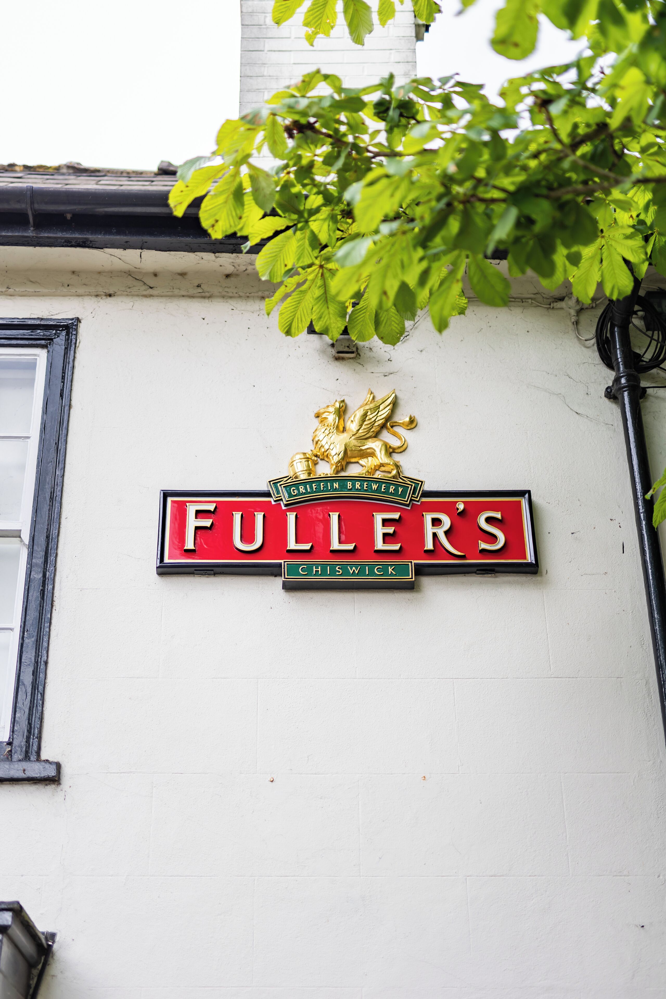 Schild für die Griffin Brauerei Fuller's an einer weißen Gebäudefassade.