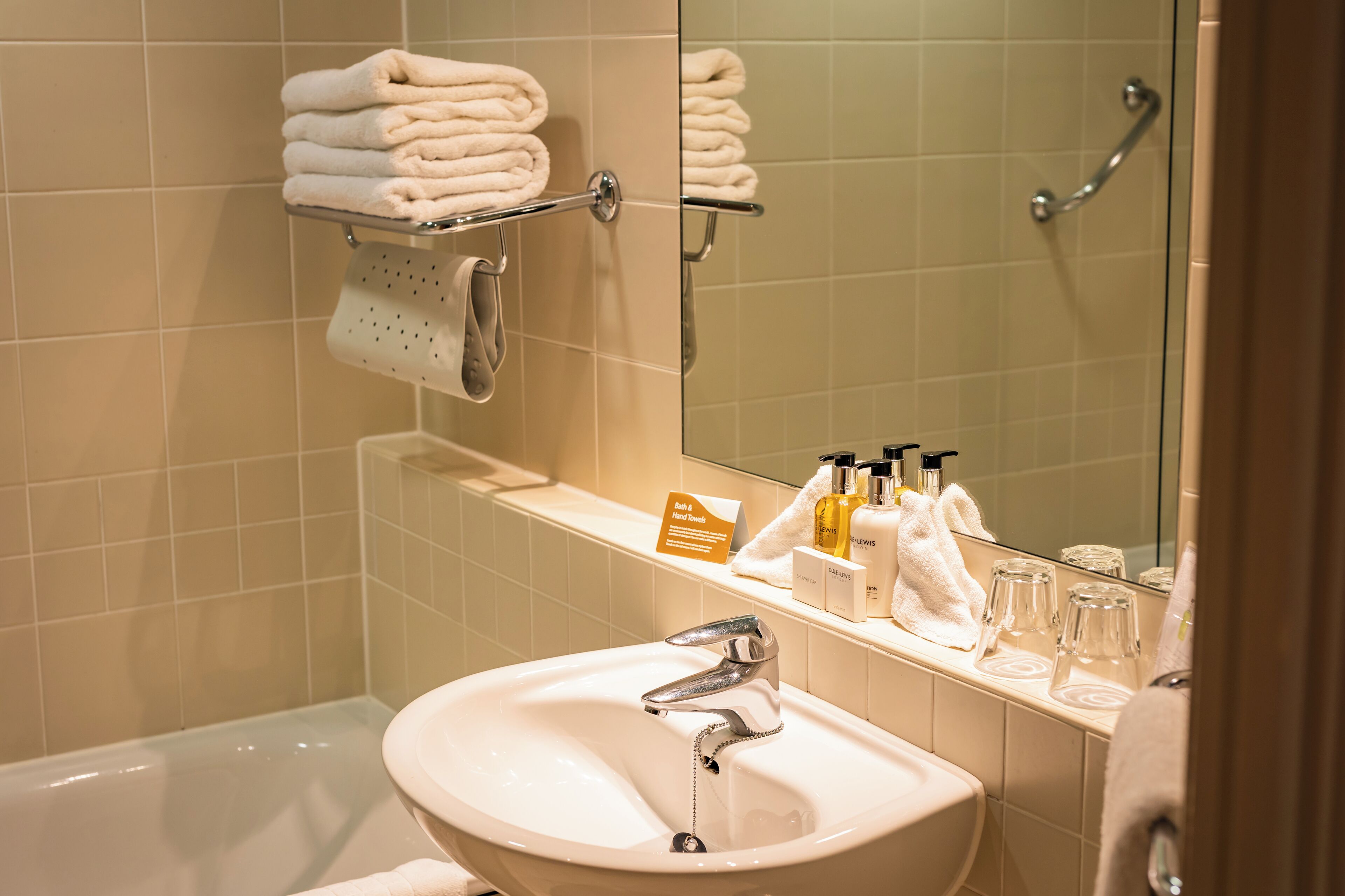 A bathroom with a sink, mirror, and a shelf with toiletries.