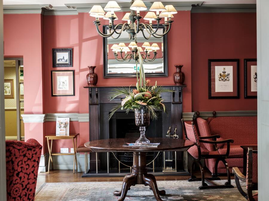 A formal dining room with a round table, chairs, a chandelier, framed pictures, and a fireplace.