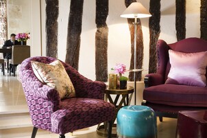 A modern lobby with a purple patterned armchair, a blue ottoman, and a floor lamp.