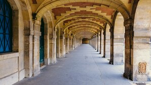 A corridor with arches and columns, leading to a distant end. - Les Tournelles (Paris)