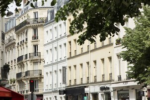 A multi-story hotel with balconies, a sign for 'Les Toulleries Hotel', and a 'Simon' store on the ground floor.