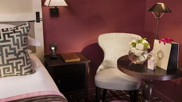 Una habitación de hotel con una cama, una mesita de noche, una silla, una mesa y una lámpara.