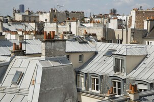 A densely packed urban area with multiple buildings featuring flat roofs, some with skylights and chimneys.