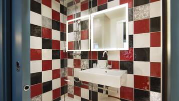 A bathroom with a checkered tile wall, a white sink, and a mirror.