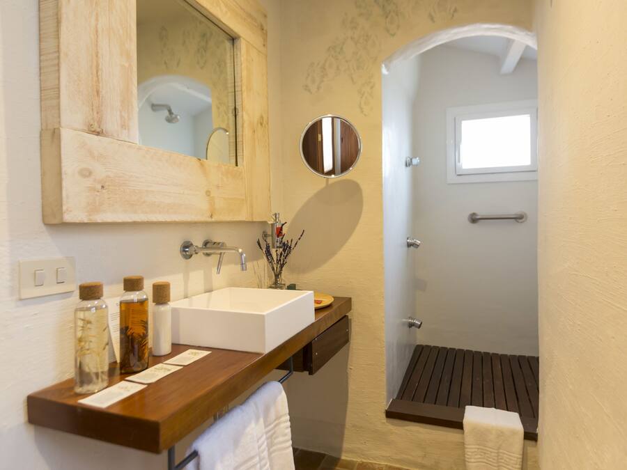 Une salle de bain avec un meuble-lavabo en bois, un grand miroir, un lavabo blanc et un espace douche.