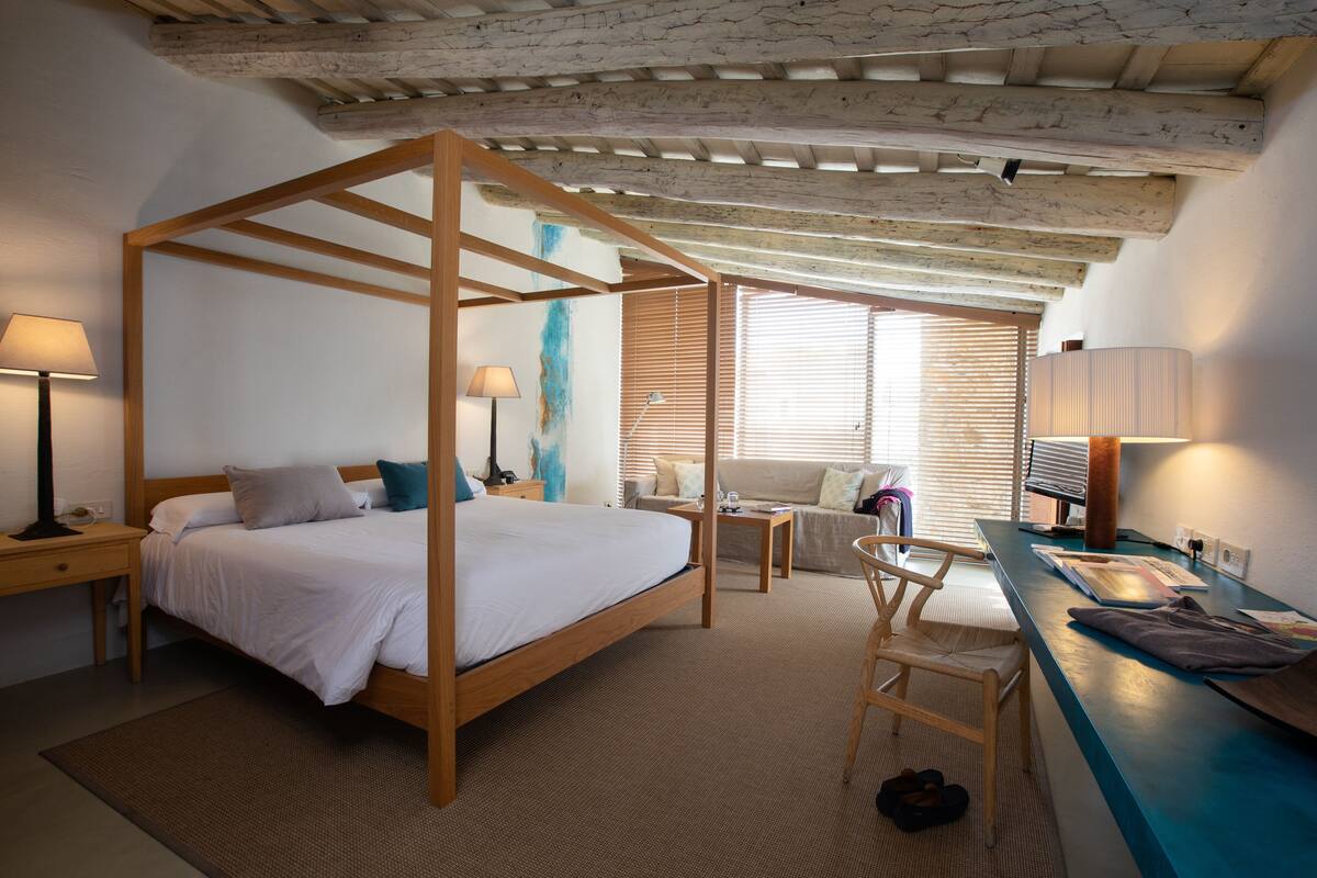 Une chambre à coucher avec un lit à baldaquin en bois, un bureau et une chaise.