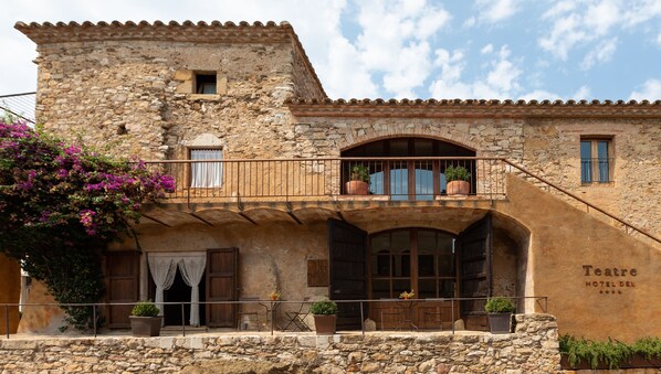 Un edificio de piedra con un balcón, una puerta de madera y un cartel que dice 