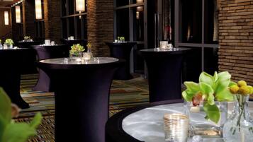 A hotel lobby with round tables, chairs, and a patterned carpet.