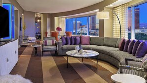 A modern living room with a large curved sofa, a round coffee table, and a television.