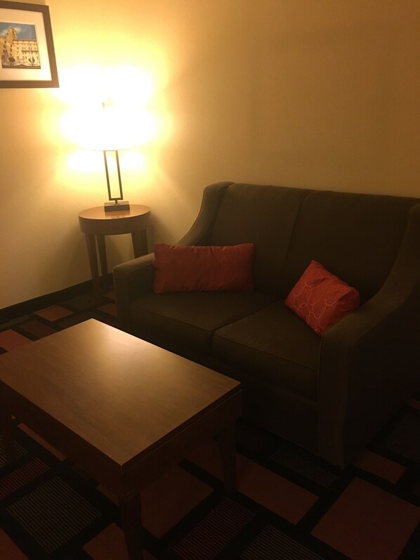 Una sala de estar con un sofá, una mesita y una lámpara.
