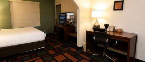 A hotel room with a bed, desk, chair, lamp, and a television.