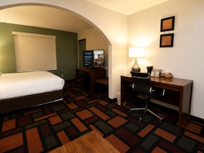A hotel room with a bed, desk, chair, lamp, and a television. - Quality Inn & Suites Malvern (Malvern)