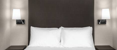 A hotel room with a large bed, two bedside tables, and wall-mounted lamps.