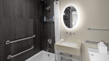 A modern bathroom with a bathtub, a shower, a sink, and a mirror.
