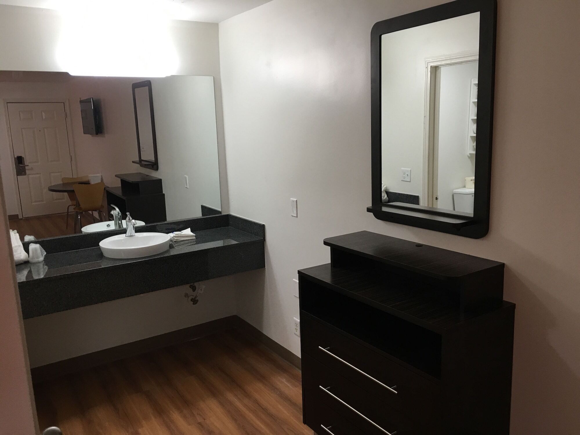 A modern bathroom with a white sink, black vanity, and a large mirror.