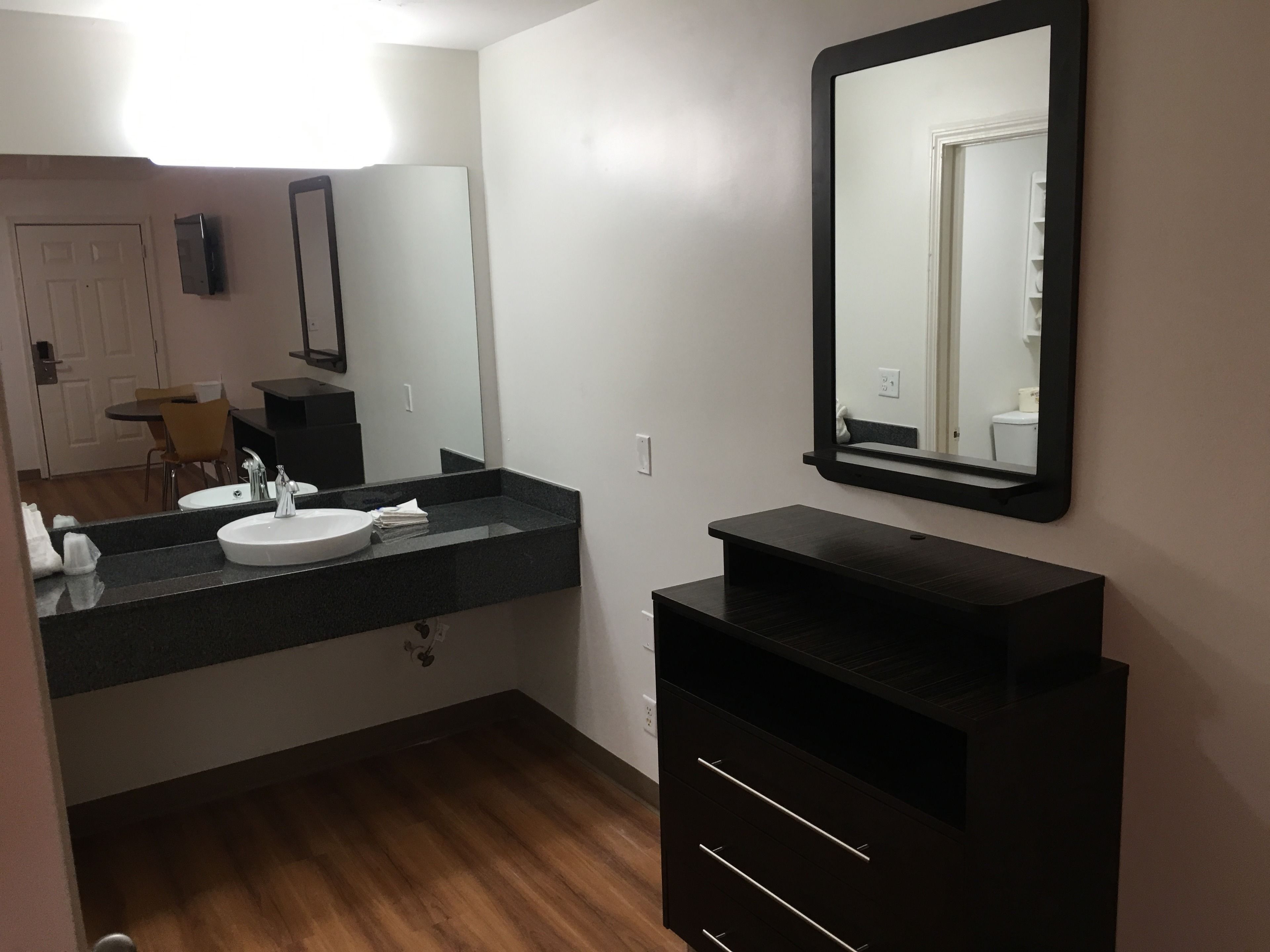 A modern bathroom with a sink, mirror, and dark cabinetry.