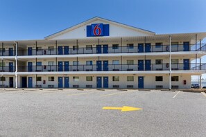 Un motel con un letrero que dice '6', varios pisos y un estacionamiento con flechas direccionales.