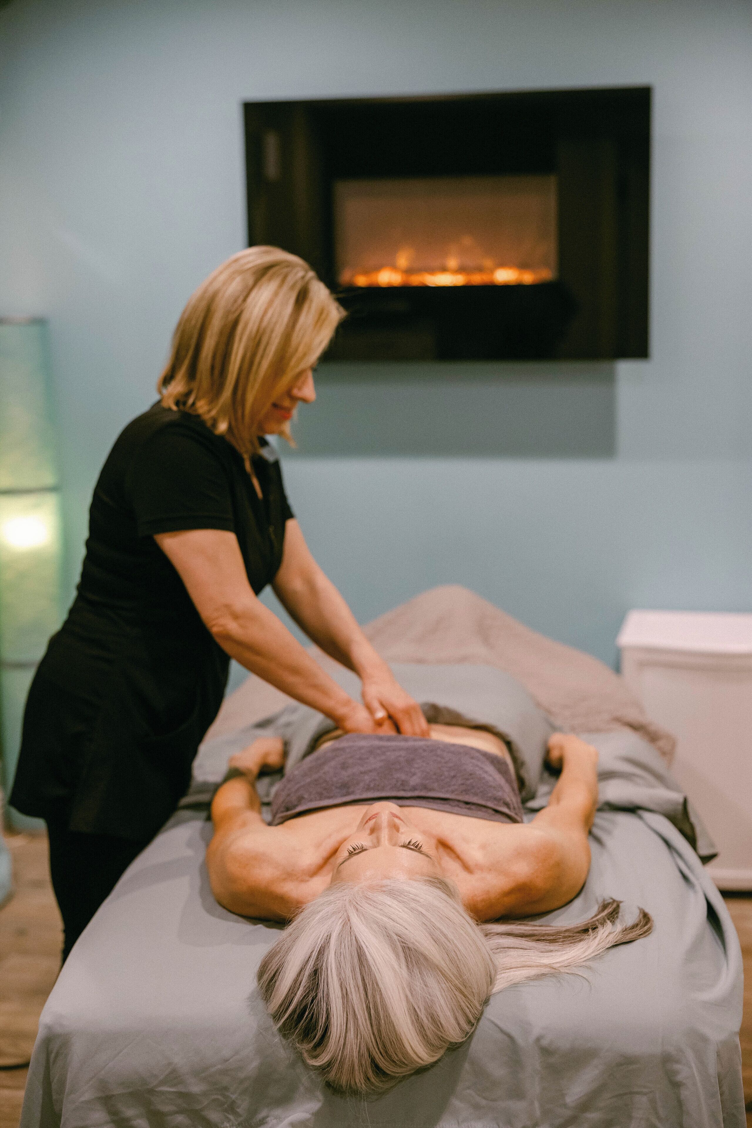 A massage therapy session in a room with a fireplace.