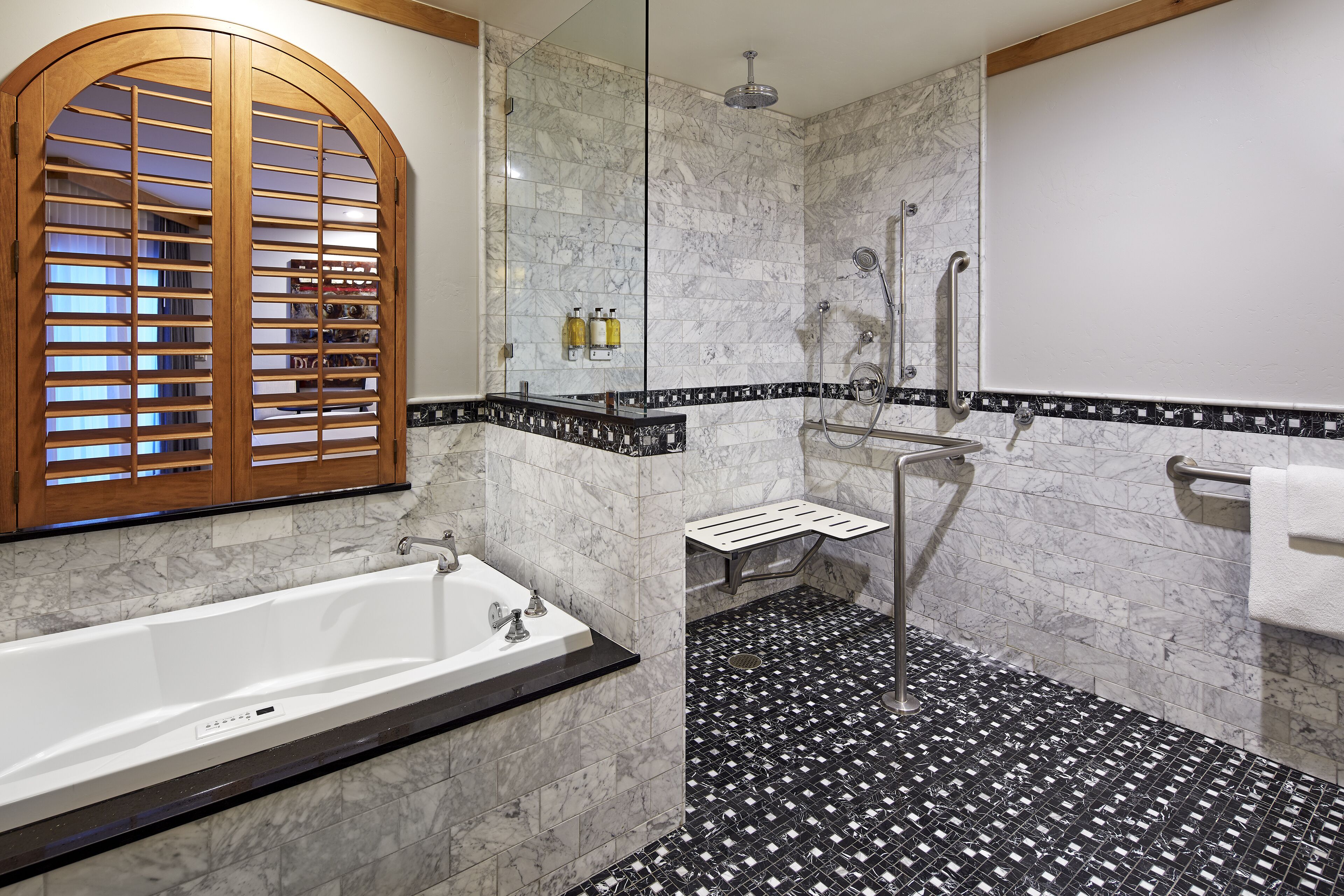 Un baño con bañera, ducha con puerta de cristal y suelo de baldosas.