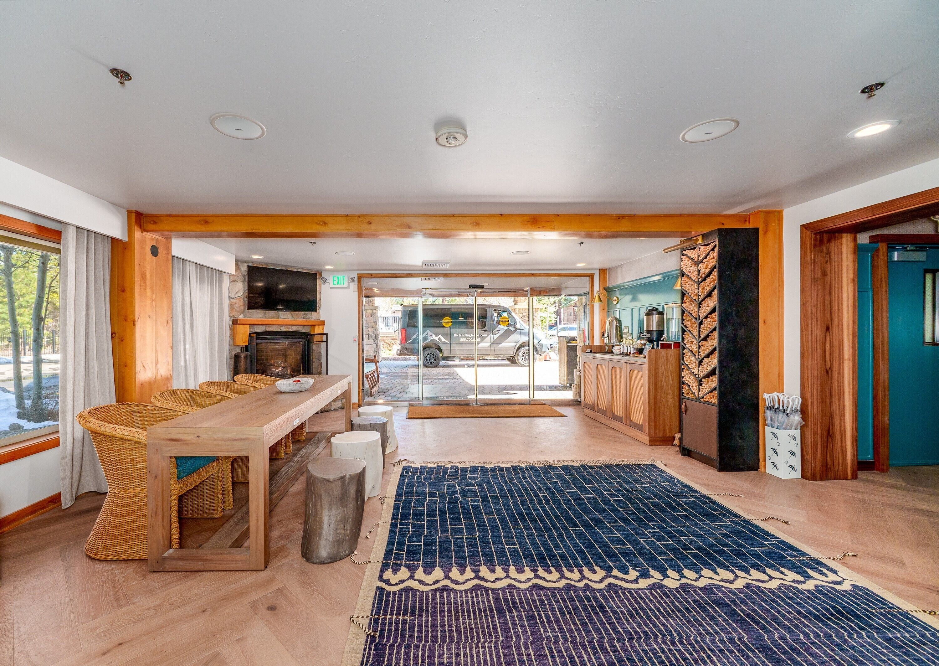 A spacious room with a wooden dining table, wicker chairs, a fireplace, and a view of the outside.