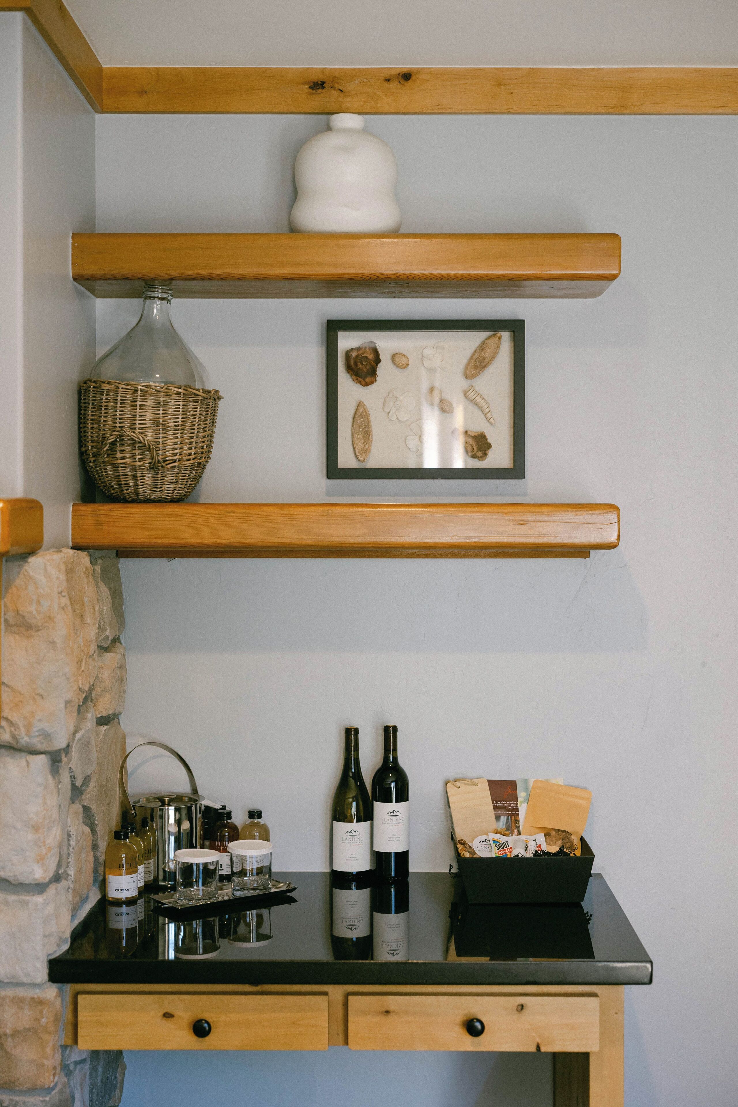 A kitchen counter with a wine bottle, a basket, and a framed picture.