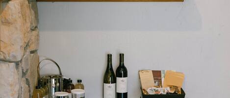 A kitchen counter with a wine bottle, a basket, and a framed picture.