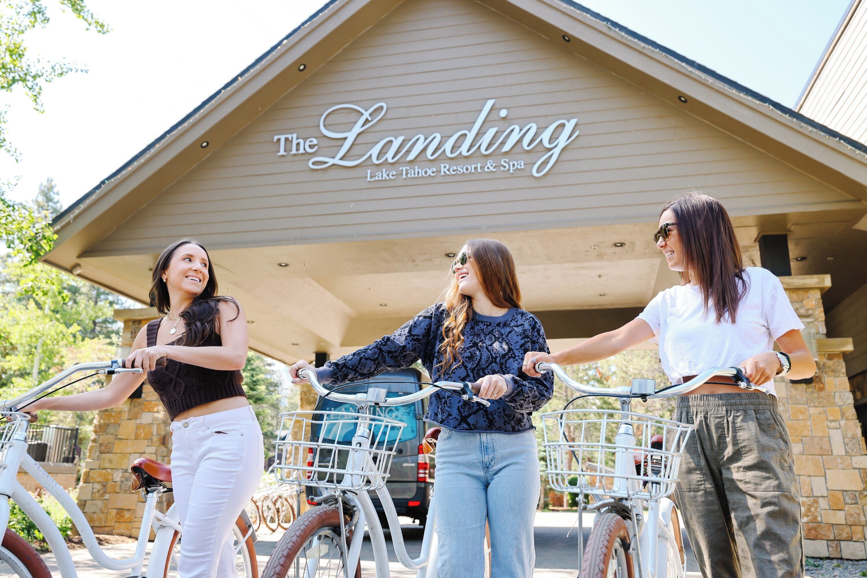 Drei Personen stehen vor einem Gebäude, an dem ein Schild mit der Aufschrift 'The Landing Lake Tahoe Resort & Spa' zu sehen ist.