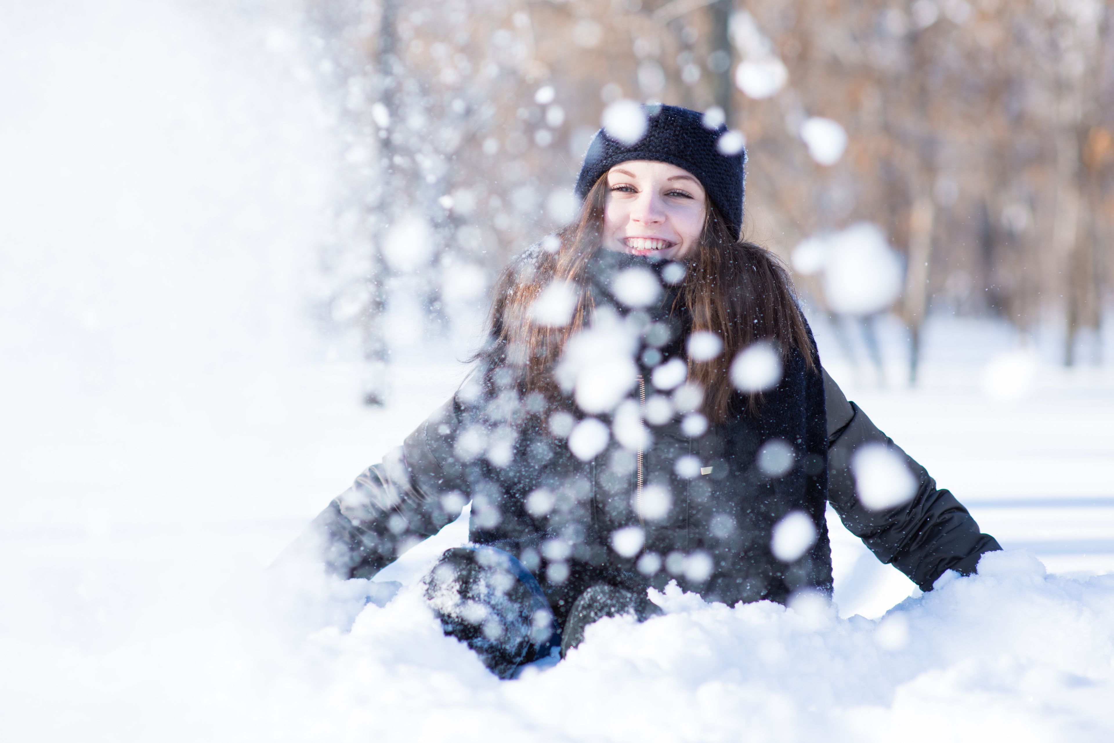 Uma pessoa sentada na neve, vestindo uma jaqueta e um gorro pretos.