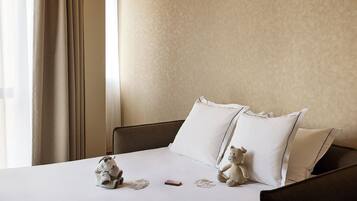 Un lit bien fait, avec une literie blanche, deux oreillers et deux peluches posés sur le lit.