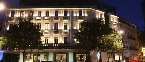A hotel with a classic facade, multiple balconies, and a sign indicating it is a hotel in France.