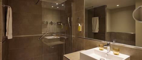 A modern bathroom with a glass-enclosed shower, a white sink, and a large mirror.