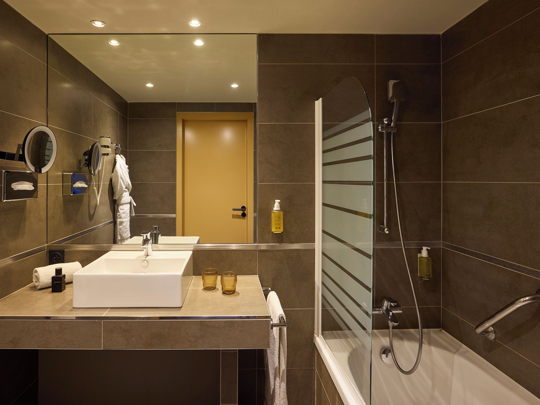 Une salle de bain moderne avec un grand miroir, deux lavabos, une douche et des toilettes.