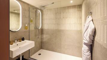 Un baño moderno con ducha de vidrio, lavamanos blanco y toallero.