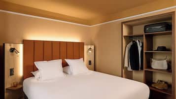 A hotel room with a bed, a wardrobe, and a nightstand with a lamp.