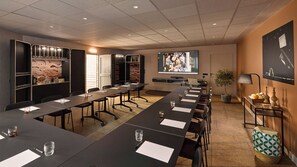 A conference room with a long table, chairs, a projector screen, and a small plant. - You Hotel de France Valence - Handwritten Collection. T3 26 (Valence)