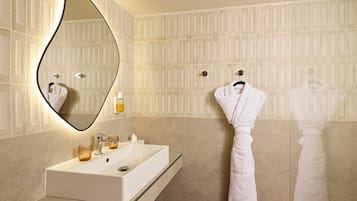 Un baño con un espejo grande, un lavabo y dos toallas colgadas en ganchos.