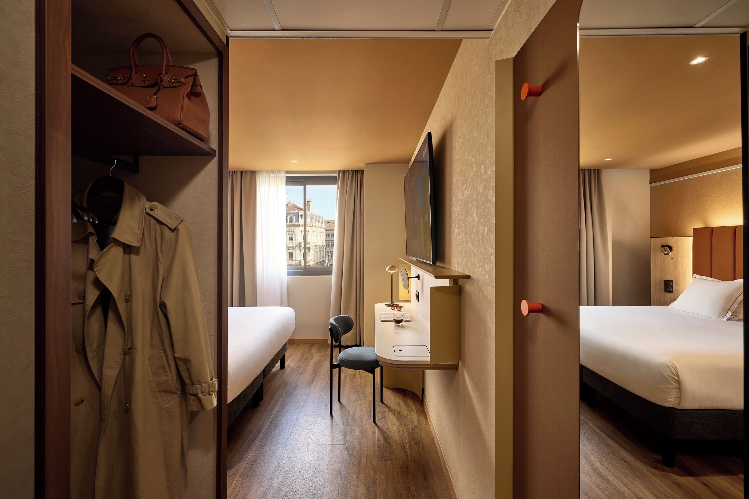 A hotel room with a bed, a desk with a chair, a TV, and a wardrobe.