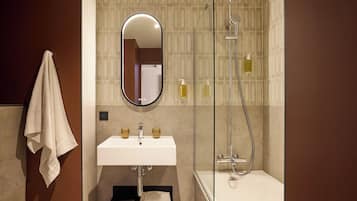 Een badkamer met een wastafel, spiegel, handdoekhouder en douche.