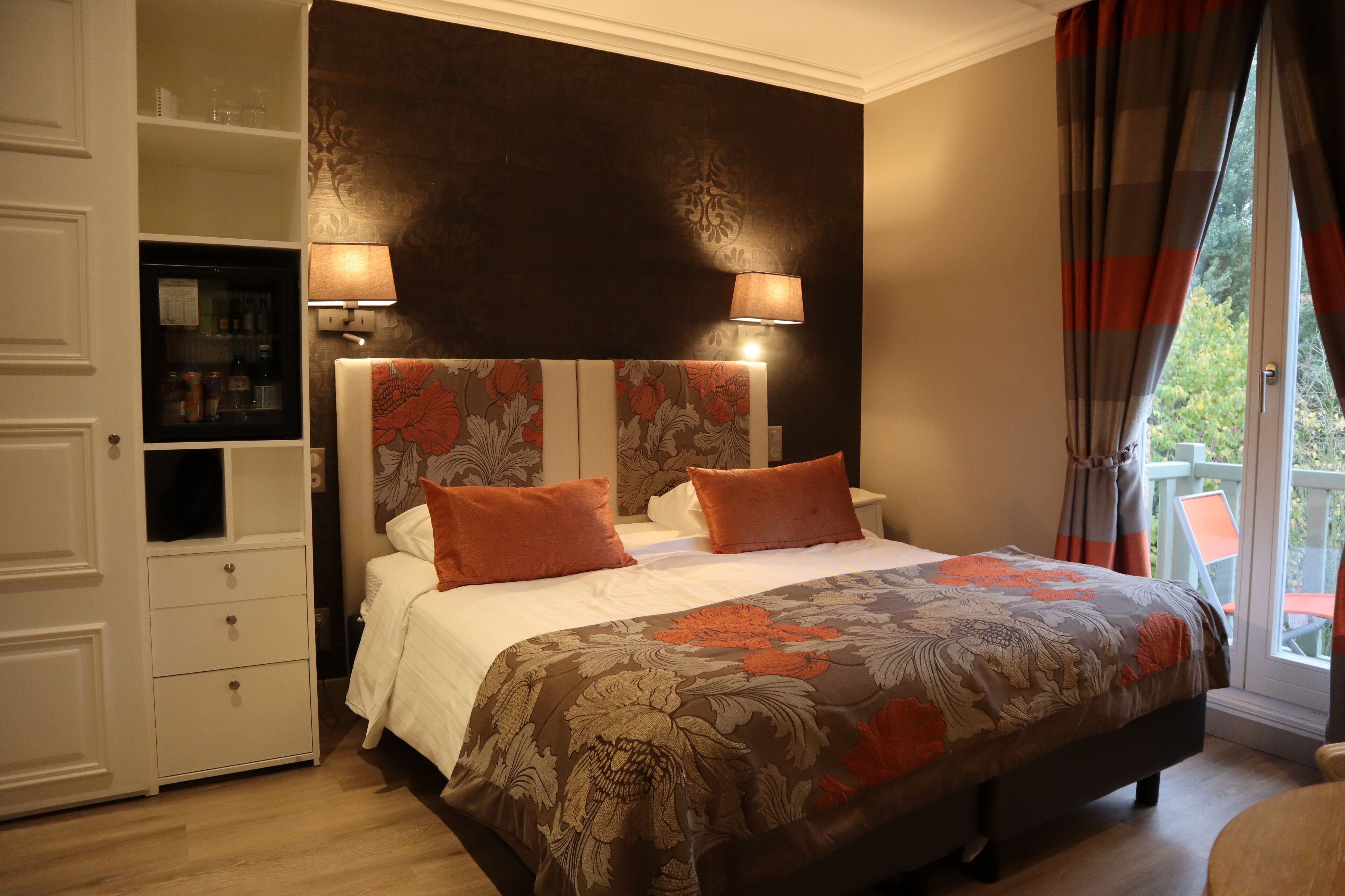 A bedroom with a large bed, two bedside lamps, a nightstand, and a built-in wardrobe.