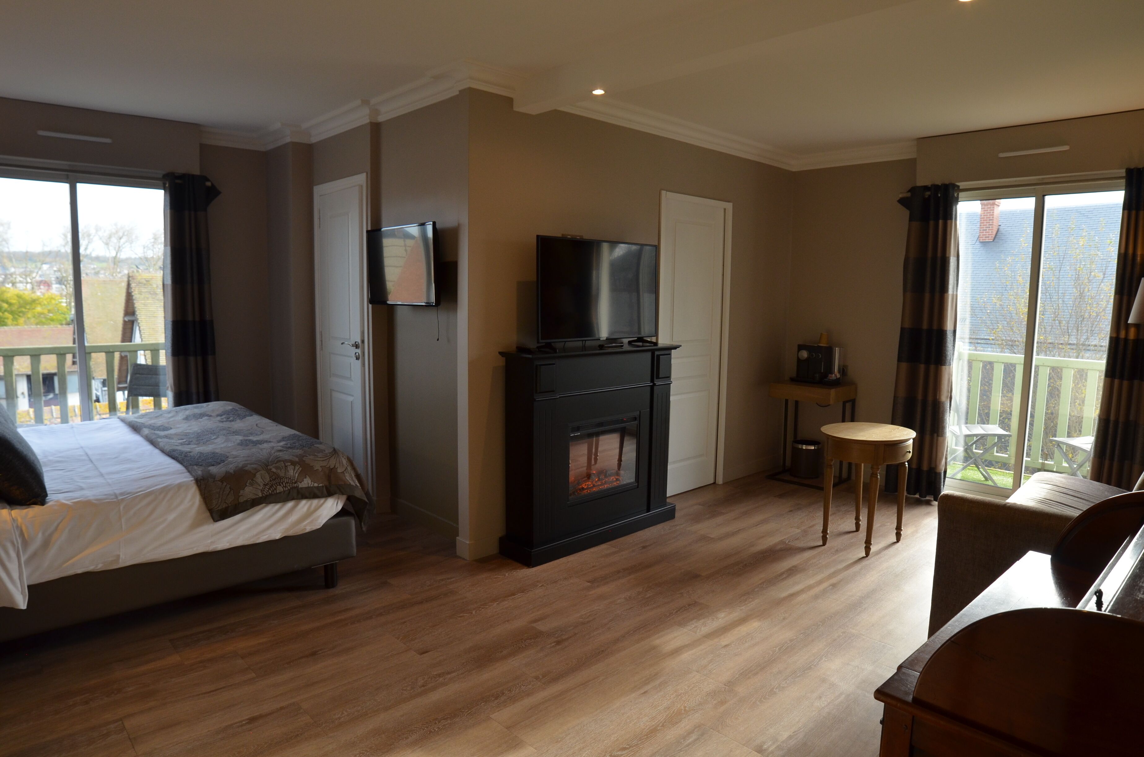 A hotel room with a bed, a fireplace, a television, and a balcony with a view.