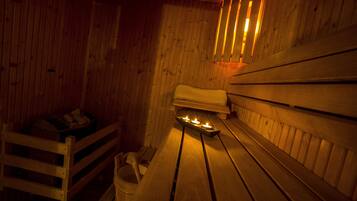 Una sala de sauna con bancos de madera, un banco con una toalla y un banco con una cesta.