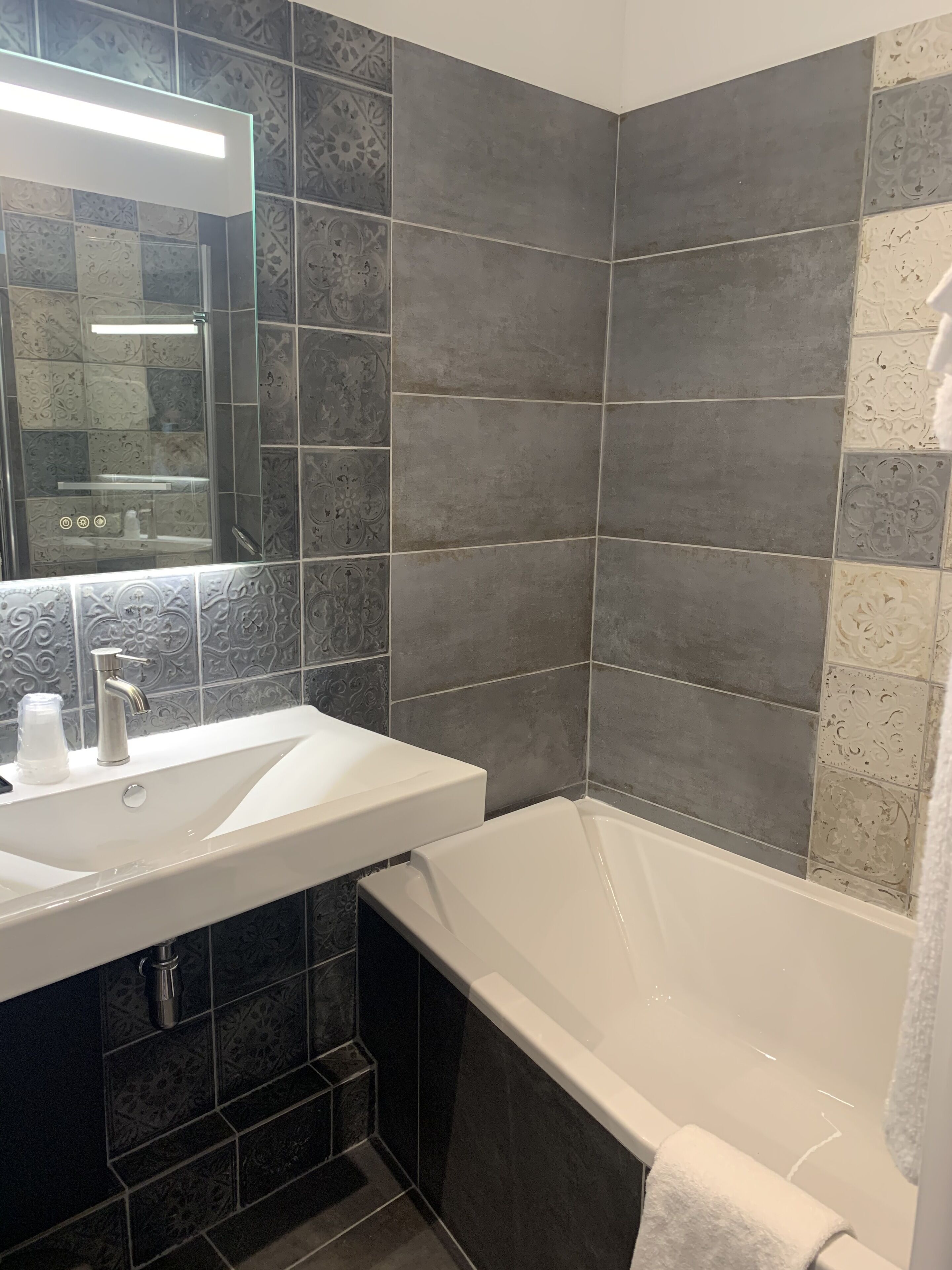Un baño con lavamanos blanco, espejo y bañera.